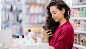 A young woman uses the adverse events contact information on the label of a cosmetics bottle.