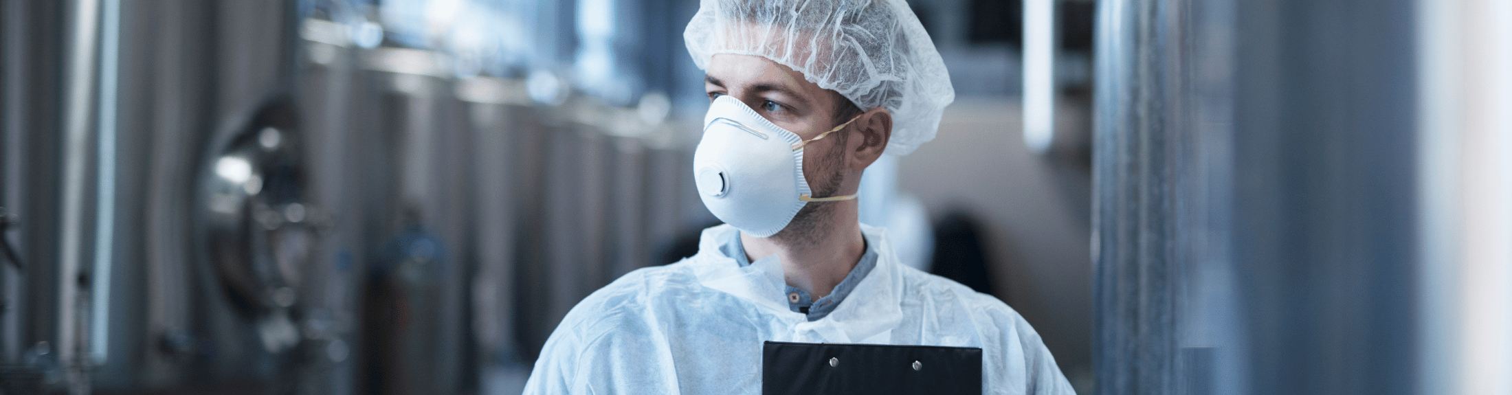 Masked and gloved worker overseeing food safety management standards based on Global Food Safety Initiative (GFSI).