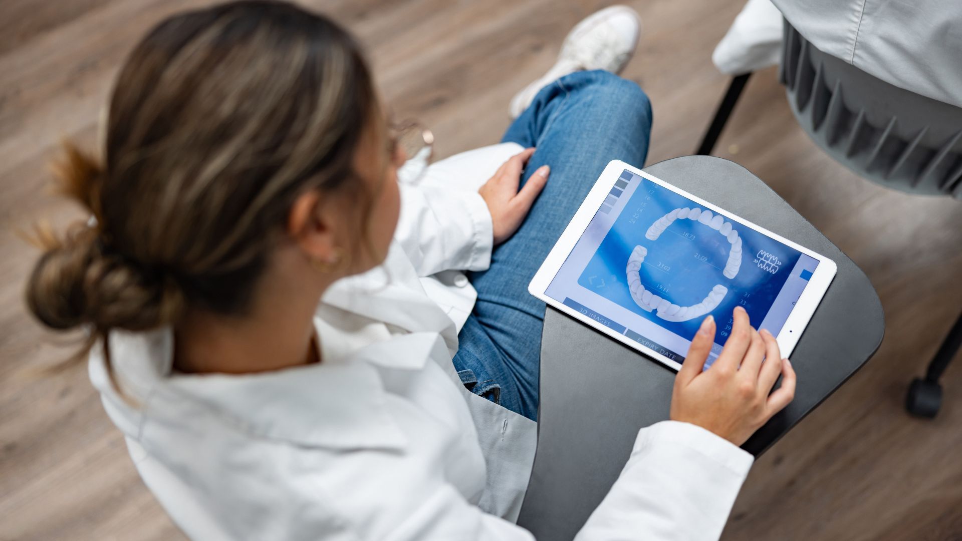 A dentist sits as she interacts with dental software and AI tools.